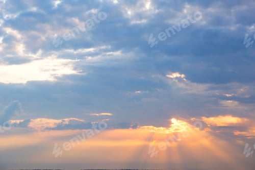 Preview: Orange rays of the sun through cumulus clouds in the sky at sunset in summer. Heavenly magic light.