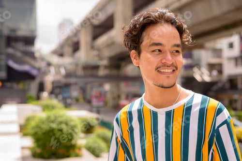 Preview: Portrait of handsome multi-ethnic young man wearing colorful shirt outdoors during summer in city