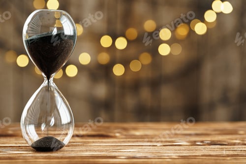 Preview: Hourglass on wooden desk against blurred lights