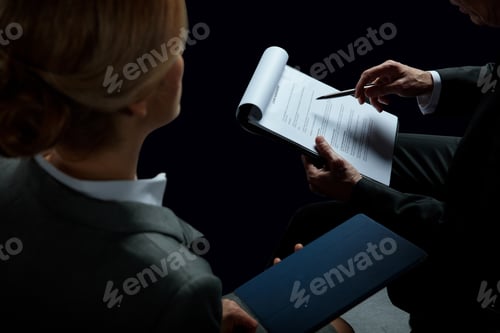 Preview: Cropped shot of blonde businesswoman looking at businessman signing contract isolated on black