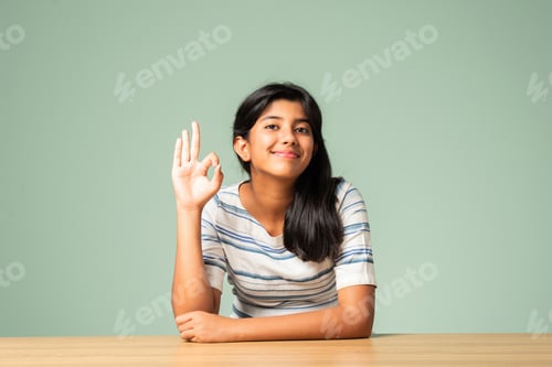 Vista previa: Niña asiática india que muestra que está bien, signo perfecto o con el pulgar hacia arriba