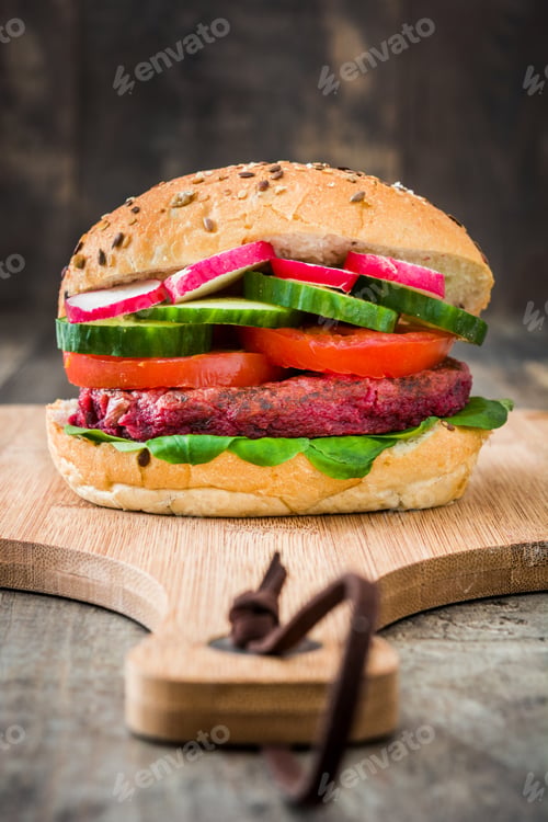 Preview: Delicious vegetarian beet burger with fresh vegetables on a wooden board