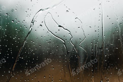 Preview: raindrops and trickles of water reflected by natural light through the glass on a sad and gloomy