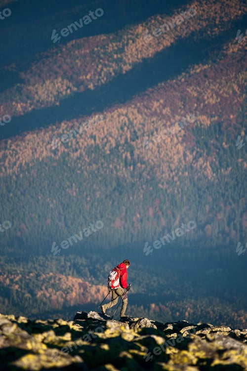 Preview: Male backpaker walking on the rocky top of the mountain