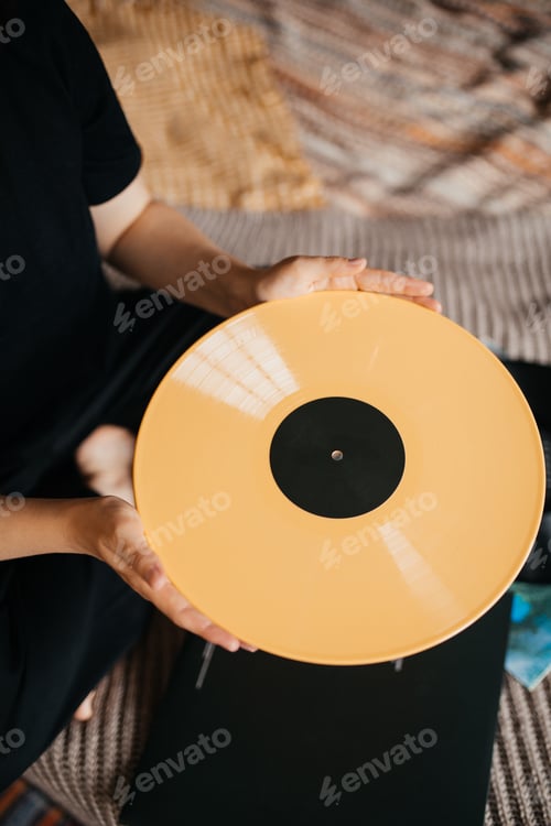Preview: Young woman holding vinyl records in a room with black wall decorated with vintage vinyl records