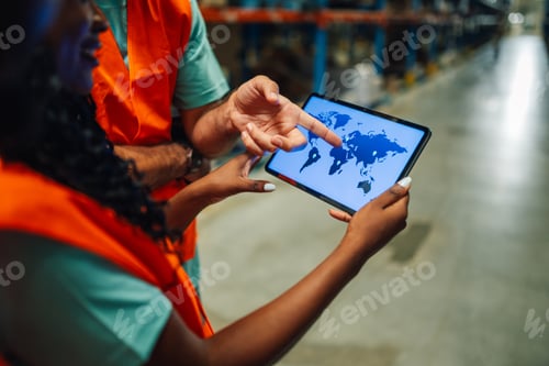 Preview: Warehouse workers using digital tablet showing world map for logistics and delivery