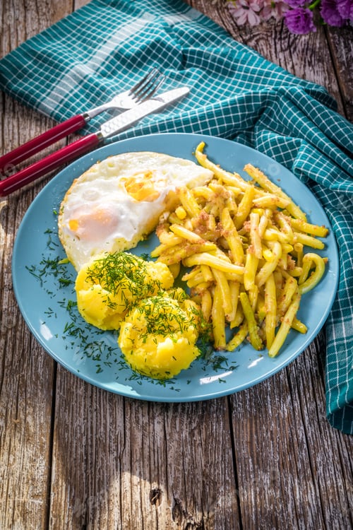 Preview: Fried egg served with boiled potatoes and yellow beans.