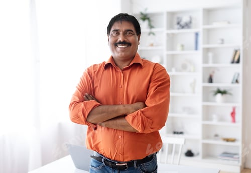 Preview: Handsome cheerful mature indian man posing at home office