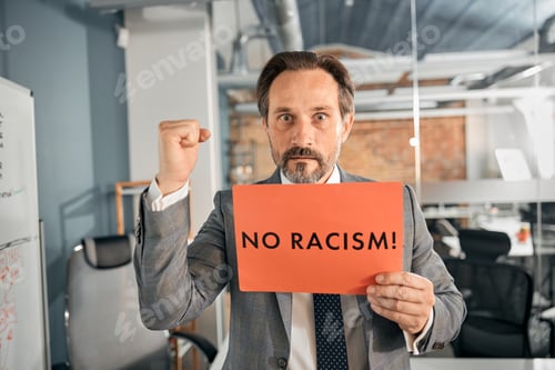 Preview: Businessman holding a poster with the word no racism