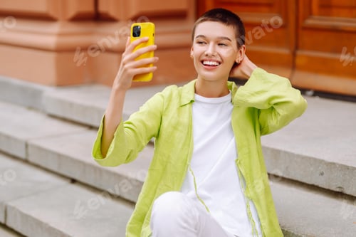 Preview: A cheerful tourist enjoys the urban atmosphere of the streets of Europe, takes selfie on smartphone.