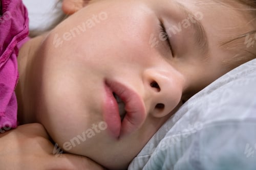Preview: Close up of a face of pretty little child girl with slightly open mouth and scattered around hair