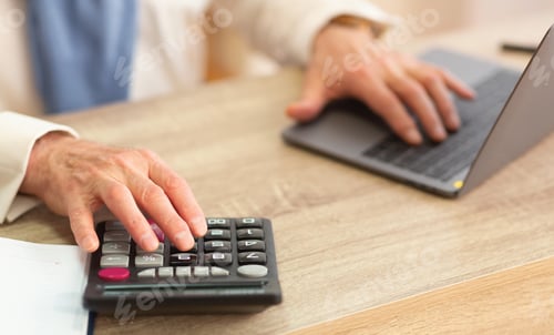 Preview: Elderly Man's Hands Using Calculator And Laptop In Office