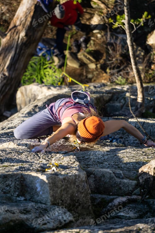 Preview: Female Rock climber climbing on the edge of the cliff during a sunny winter sunset
