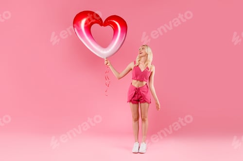 Preview: Blonde in pink looking up at heart balloon