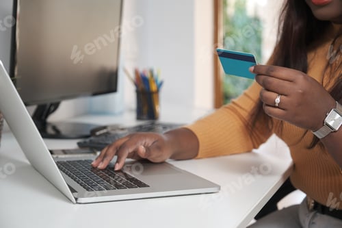 Preview: Unrecognizable woman shopping online and paying with a credit card.