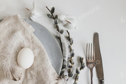 Preview: Stylish Easter table setting flat lay. Natural easter egg, willow branches, feathers on modern plate