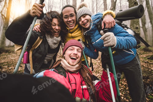 Preview: Multiracial happy friends with backpacks hiking in the forest