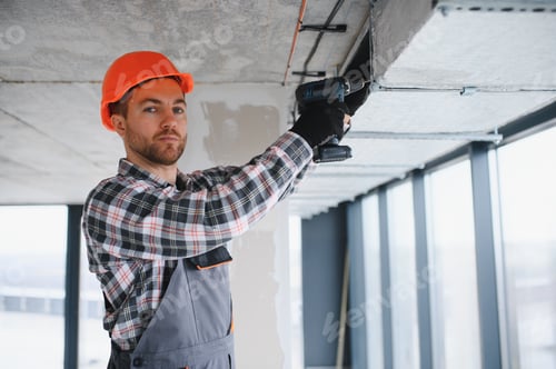 Preview: Construction worker installing ventilation system with power drill