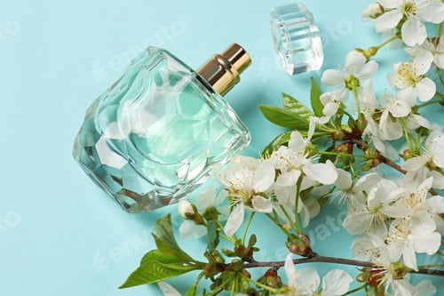 Vista previa: Bottle of aromatic perfume and twigs with beautiful flowers on light blue background, flat lay
