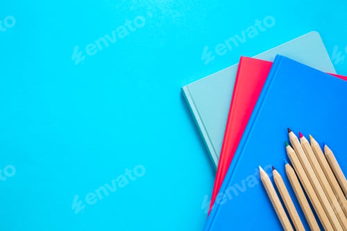 Preview: Notebooks and pencils on a blue background, top view.