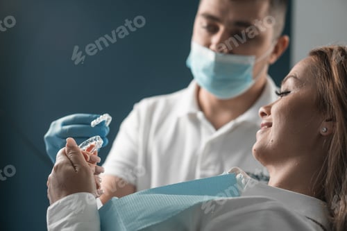 Preview: A dentist shows veneers to female patient as method correcting teeth and taste. Mouth guards for