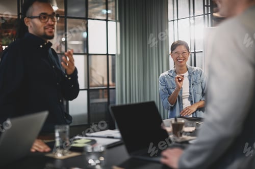 Preview: Asian businesswoman smiling during a presentation with diverse colleagues