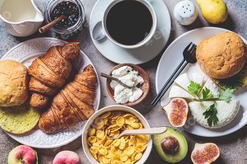 Preview: Breakfast table with cornflakes, croissants, fruit, cheese and cup of coffee.