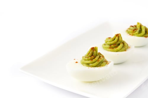 Preview: Delicious deviled eggs with guacamole topping and paprika garnish on white plate