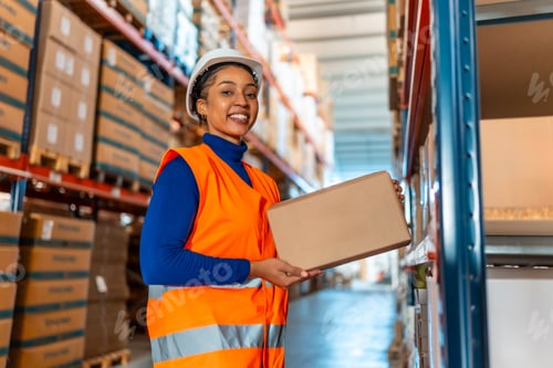Preview: Female warehouse worker holding carton box, smiling in logistics