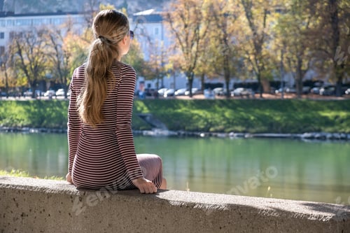 Preview: Young woman in a casual dress and sunglasses resting outdoors on a warm autumn day