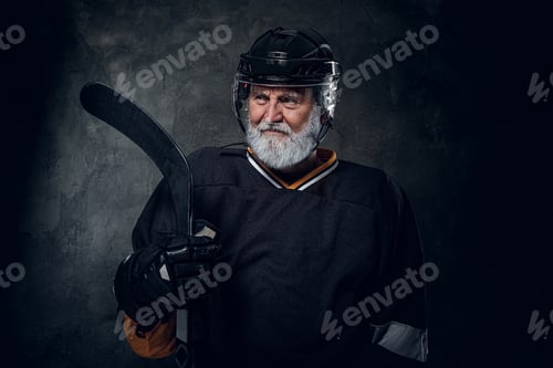 Preview: Elderly sportsman dressed in uniform and helmet holding stick