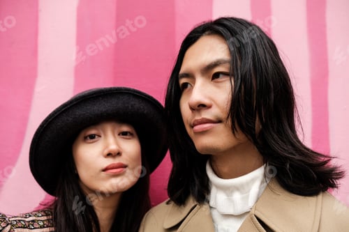 Preview: Young couple posing together in front of pink wall