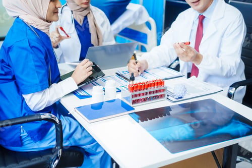 Preview: Two Muslim female doctors meet with an Asian male doctor to discuss an X-ray, blood vessel samples