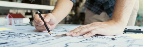 Preview: Interior designer or architect reviewing blueprints and holding pencil drawing