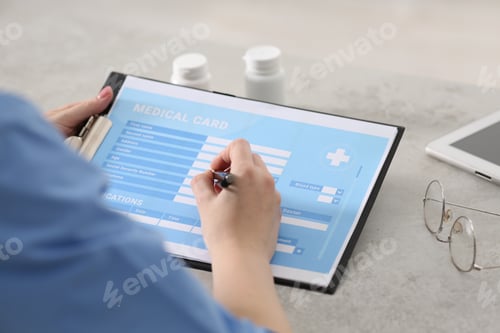 Preview: Doctor filling patient's medical card in clinic, closeup