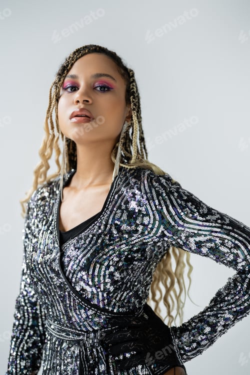 Preview: party style, african american woman with bold makeup posing with hand on hip, grey background