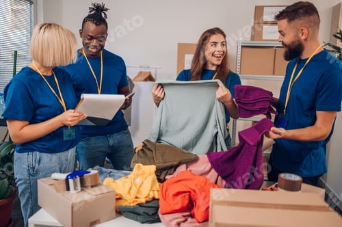 Preview: Diverse volunteers working in a charity donation center and packing clothes and food