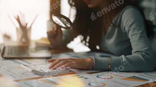 Preview: Woman Analyzing Financial Data Using Calculator and Magnifier