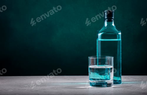 Preview: Dry gin in glass with sapphire blue bottle on dark green background