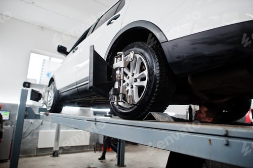 Preview: American SUV car on stand for wheels alignment camber check in workshop of service station.