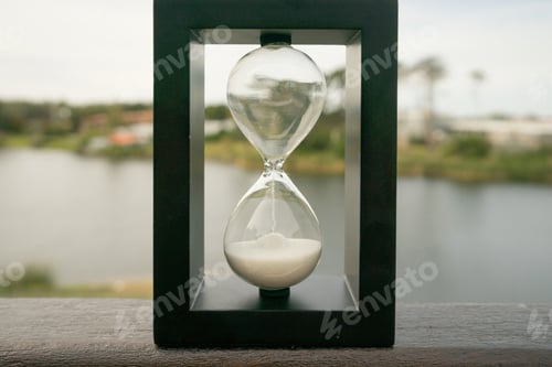 Preview: Beautiful shot of a classic vintage Hourglass or Sandglass Clock with nature in the background