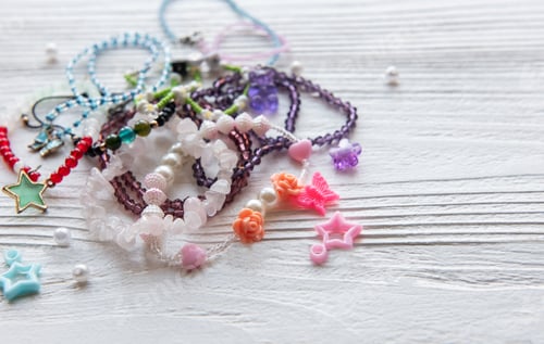 Preview: Colorful handmade jewelry laid out on a wooden surface showcasing various beads and charms