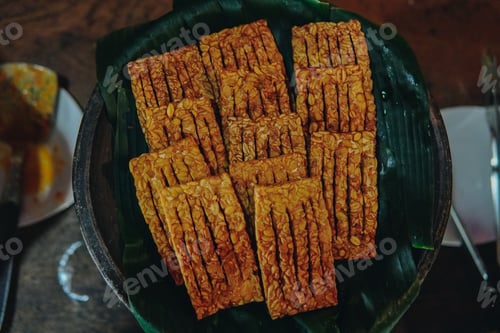 Preview: A plate of fried tempe, traditional snack from Indonesia with a banana leaf underneath.