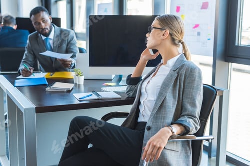 Preview: side view of beautiful businesswoman talking by smartphone in office
