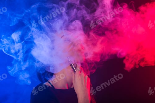 Preview: Portrait of young woman in neon blue and red smoke with vape or e-cigarettes