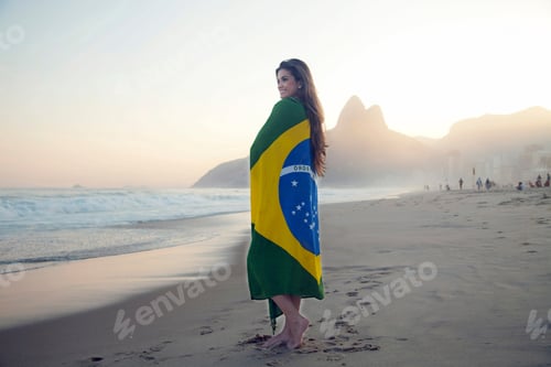 Preview: Young woman on beach, wrapped in Brazilian Flag