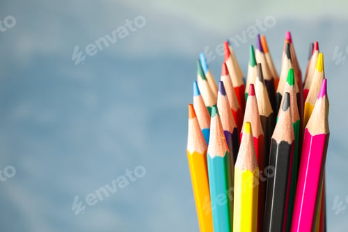 Preview: Multicolored pencils against light blue background, closeup