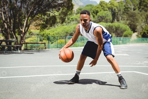 Preview: Full length of teenage boy practicing basketball