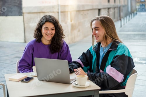 Preview: Two people using laptop and mobile phone while sitting outdoors at a coffee shop