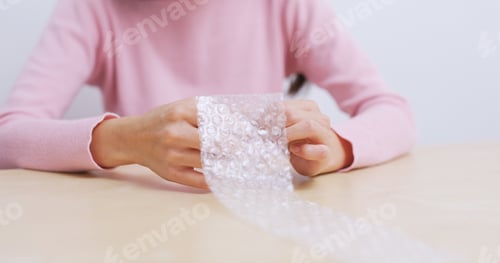 Preview: Woman play with bubble wrap at home